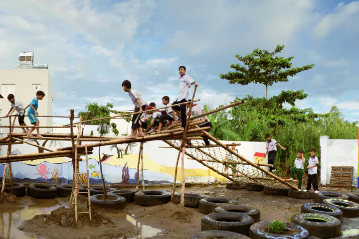 Image shows several children playing on a playground structure made from bamboo
