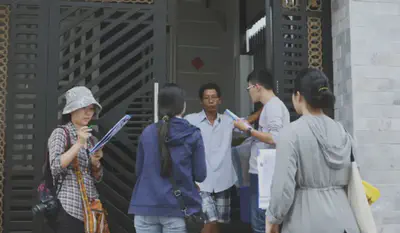 Four researchers at the door of a resident's house speaking with the resident.