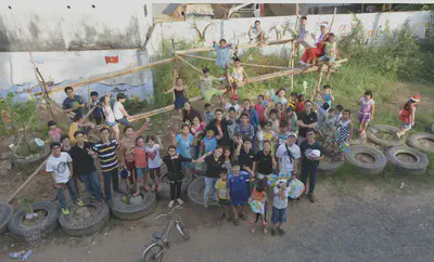 Group of residents, children, students and researchers posing for a picture with the bamboo structure. About 40 plus people in the photo.