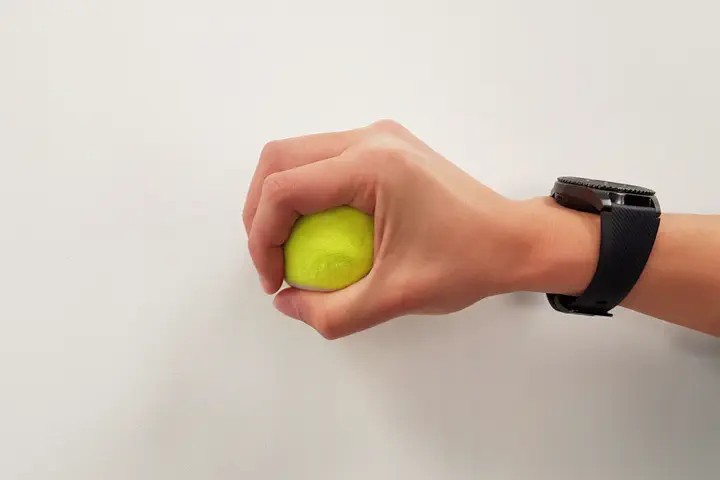User wearing smartwatch with fSense and grasping a tennis ball