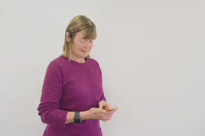 Older adult lady user uses Prompto app, wearing the E4 wristband and bone conduction headset.