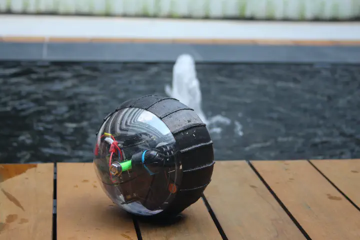 Image of Salamander, a spherical rolling robot, with a backdrop of a water fountain.